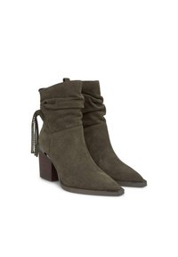 Zielono-oliwkowe zamszowe botki do kostek o luźnym fasonie, ze spiczastym noskiem i słupkowym obcasem. Posiadają frędzle i ćwieki po bokach.