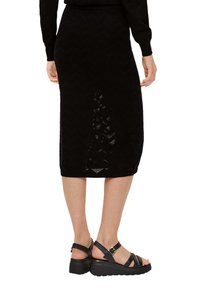 Jupe midi en tricot noir avec un motif en chevrons, avec un ourlet se terminant en dessous du genou et un tissu léger.