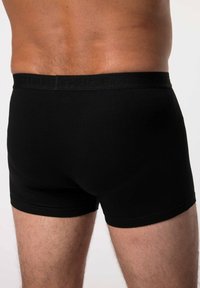 Boxer in cotone nero con una texture liscia e una ampia vita elastica che presenta un logo in rilievo discreto.
