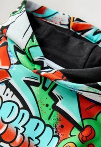 Hoodie z graficznym kołnierzem, charakteryzujący się żywym wzorem w odcieniach zieleni, czerwieni i czerni. Wykonany z miękkiego materiału z wygodnym czarnym podbiciem.