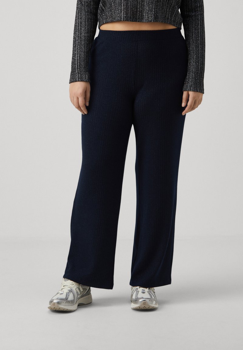 Navy ribbed wide-leg pants made of soft fabric with an elastic waistband, paired with light-colored athletic shoes.