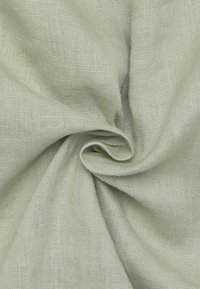 Lichtgroene linnen stof met een gladde textuur, gekenmerkt door een los geweven patroon en een zachte draperende uitstraling.