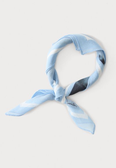 Écharpe en soie bleu clair à motifs avec des accents blancs et foncés, nouée en un nœud lâche sur fond blanc.