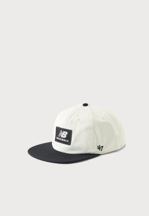 Hvid og sort New Balance baseballkasket med sort skygge og patch-logo foran, vist mod en enkel lys baggrund.