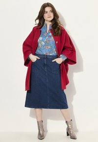 Prenda exterior roja sobre una blusa floral azul, combinada con una falda de mezclilla y botas con tobillo plateadas. El conjunto exhibe colores vibrantes y texturas variadas.