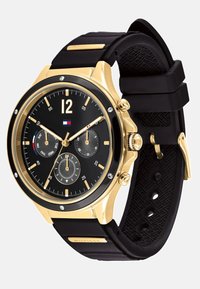 Montre pour homme avec un boîtier en acier inoxydable doré, un cadran noir avec des index argentés, et un bracelet en silicone noir avec des détails texturés.