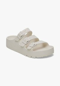 Sandal in schiuma bianca con tre fettucce regolabili e suola piatta e testurizzata. Superficie liscia con dettagli in fibbia. Progettato per comfort e facilità di utilizzo.