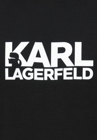 Černé bavlněné tričko s výrazným bílým textem "KARL LAGERFELD" a siluetou profilu vlevo od názvu.