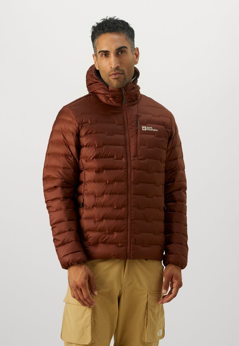 Brown insulated jacket with a puffy design, hood, zip closure, and logo on the chest. Worn over light beige cargo pants.