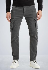 Graue Cargo-Hosen mit schmalem Schnitt, mehreren Seitentaschen und glatter Textur. Kombiniert mit weißen Turnschuhen für einen lässigen Look.