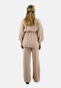 Beige gebreide twee-delige set met een geribbelde textuur, oversized cardigan met een strik taille, en wijde broek met bijpassende strepen.