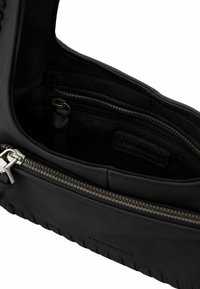 Interno di una borsa in pelle nera con una tasca con zip, rivestimento strutturato e finitura liscia, con un'etichetta di marca ben visibile.