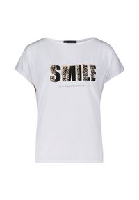 T-shirt blanc à manches courtes mettant en avant le mot "SMILE" en lettres noires en gras et en imprimé léopard, avec un texte plus petit en dessous dans un style cursif.