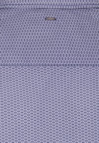 Patterned fabric with repeated small diamond shapes in blue and white, featuring a small metal tag with the brand name "ETRO" near the top center.