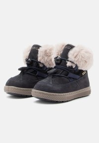 Bottes chelsea en daim bleu marine avec une bordure en fausse fourrure beige, des lacets élastiques et des semelles en caoutchouc texturé avec un motif en losange.
