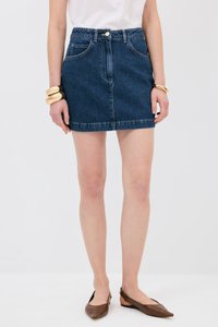 Jeansowa spódnica mini w ciemnoniebieskim kolorze, z dopasowanym pasem, przednimi kieszeniami i surowym wykończeniem. W zestawieniu z brązowymi balerinami o spiczastym nosku i złotą bransoletką.