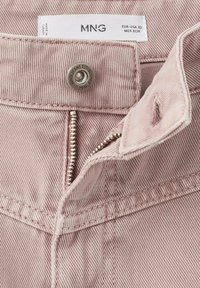 Jeans de mezclilla rosa claro con un zipper metálico, cierre en el botón superior y una sutil textura acanalada. La etiqueta dice "MNG" con información sobre la talla.