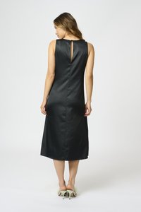 Melnas satīna bezpiedurkņu kleitas ar atvēršanu aizmugurē, midi garumā, gluda tekstūra un taisna piegriezuma. Uzsvērta ar augstpapēžu kurpēm.