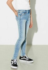 Ljusblå smala jeans med en blekt tvätt, med en klassisk femficksdesign och subtil sömnad, kombinerat med svarta kanvas sneakers.