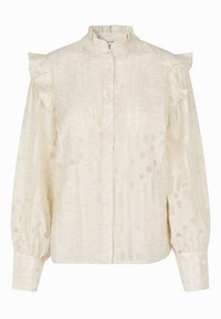 Light cream blouse with ruffled shoulder accents, standing collar, button front, and textured fabric featuring a polka dot pattern.