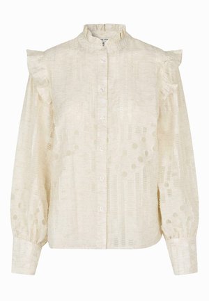 Ljus krämfärgad blus med volangdetaljer vid axlarna, hög krage, knäppning fram och textil med en prickig mönstring.