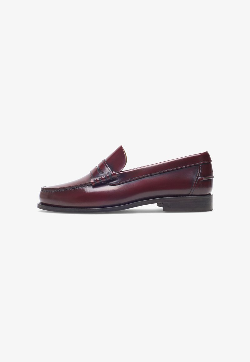 Bordeaux leren instapper met een ronde neus, gestikte details en een kleine decoratieve accent op de schacht. Platte, contrasterende zool.