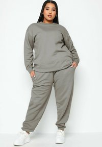 Grijze sweatshirt met lange mouwen en bijpassende joggerbroek van zachte, gestructureerde stof met elastische manchetten, gecombineerd met witte sneakers.