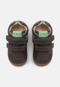 Zapatos de ante marrón para niño pequeño con acentos verdes, dos correas de Velcro, punteras redondeadas y forro interior beige. Tamaño 20 indicado en el interior.