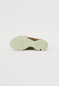 Sport shoe featuring a brown upper material with a textured finish, light green rubber outsole, and a patterned tread design for traction.