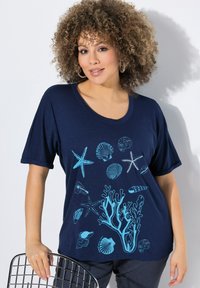 Námořnická modrá tričko s krátkými rukávy, které má světle modrý design mušlí a korálů. Měkká tkanina s volným střihem, kulatým výstřihem.
