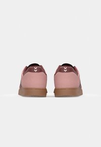 Sneaker in suede rosa con dettagli neri, suola in gomma marrone e design a tre strisce sui lati. La vista laterale mostra dettagli del marchio.