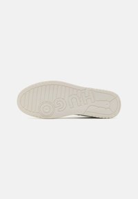 Semelle d'une sneaker en caoutchouc blanc cassé, présentant une surface texturée, des rainures horizontales et verticales, et un logo "HUGO" en relief.