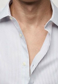 Camisa blanca de vestido con finas rayas verticales azules, cuello abotonado y el primer botón desabrochado, con una textura de tela suave y ligera.