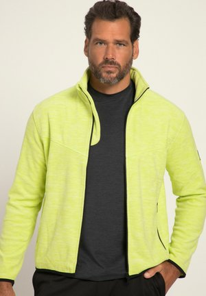 Giacca in pile verde lime con colletto zip, caratterizzata da dettagli neri e una superficie texturizzata, indossata sopra una maglietta grigio scuro.