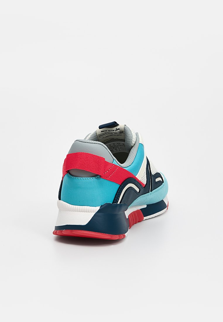 Buty sportowe w kolorze turkusowym i granatowym z szarymi akcentami, czerwonym paskiem na pięcie, białą podeszwą środkową oraz teksturowaną gumową podeszwą.