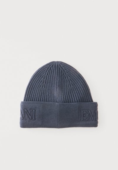 Bonnet en tricot côtelé bleu foncé avec revers plié affichant des lettres partielles embossées à l'avant sur fond blanc.