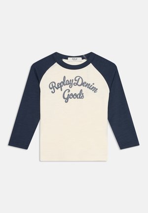 T-shirt raglan à manches longues avec manches bleu marine et corps crème, avec "Replay Denim Goods" imprimé en cursive bleu marine sur le devant.