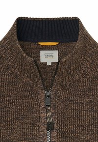 Brauner Reißverschluss-Pullover mit geripptem Kragen in Marineblau, strukturiertem Strick und schwarzem Reißverschluss. Verfügt über einen gelben Akzent unter dem Kragen.