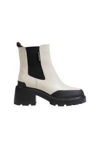 Béžové kožené kotníkové boty s černou elastickou částí na straně, robustní černou podrážkou a zaoblenou špičkou. Na elastickém panelu je štítek s logem.