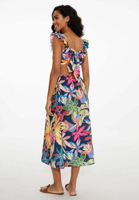 Šaty s květinovým potiskem s tmavě modrým pozadím, volánkovými ramínky, otevřeným zadním dílem se mašlí a vzdušným midi střihem. Hladká textilie.