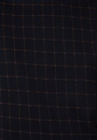 Tessuto navy con un motivo a quadretti, caratterizzato da sottili linee a griglia arancioni. La texture appare liscia e leggermente strutturata.