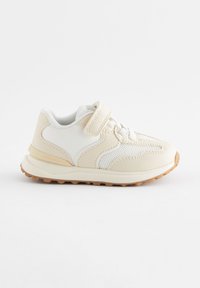 Baskets beige et blanches pour tout-petit avec mesh, empiècements synthétiques, bride velcro, lacets et semelle en caoutchouc texturée sur fond blanc.