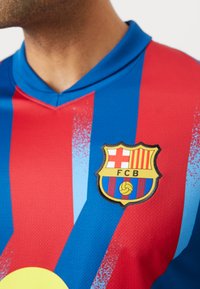 FC Barcelona marškinėliai su mėlynais ir raudonais dryžiais, pagaminti iš tekstūruoto audinio ir pristatantys komandos logotipą, aiškiai matomą krūtinėje.