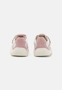 Baskets de sport en suède rose et synthétique blanc avec des détails texturés, semelles en caoutchouc et lacets en tissu. Présente une languette au niveau du talon.