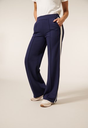 Hoge taille, marineblauwe broek met wijde pijpen, zijzakken en contrasterende witte streepdetails. Gemaakt van een gladde, rekbare stof.