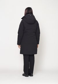 Cappotto isolato nero con cappuccio, texture liscia, lunghezza lunga, design semplice e stile minimalista. Nessun motivo o accento visibile.