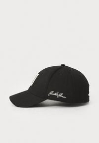 Cască de baseball neagră cu cozoroc curbat, având o literă albă mare pe față și "Jack&Jones" brodat în alb pe lateral.