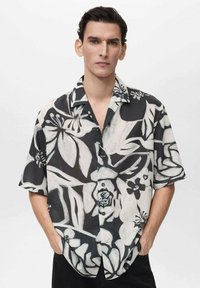Kurzärmliges Hemd im schwarz-weißen Blumenmuster, mit Knopfleiste und lockerer Passform, aus leichtem, strukturiertem Stoff gefertigt.