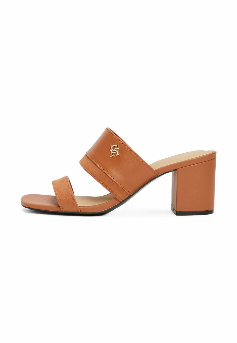 Sandalo con tacco a blocco in pelle color tan, con due cinturini, che mette in mostra un accento con logo dorato e una texture liscia. Design open-toe.
