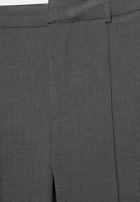 Detailní záběr na tkaninu v barvě uhelně šedé na přesně střižených kalhotách s poutkem na opasek a předními švy.